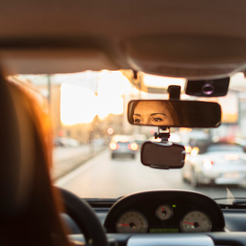 City traffic with rear view mirror reflection of a woman driver